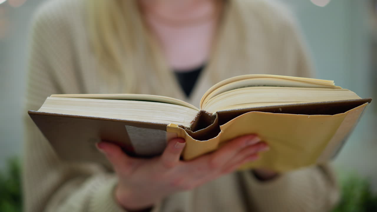 현대적인 구조와 초록색 장식 꽃이 배경에 흐릿한 청바지 바지를 입고 새로운 페이지로 돌아가는 색 여자의 가까운 손 시각