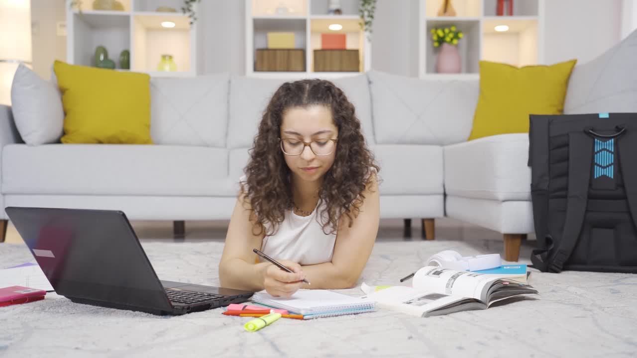 Female student working between paper and laptop.