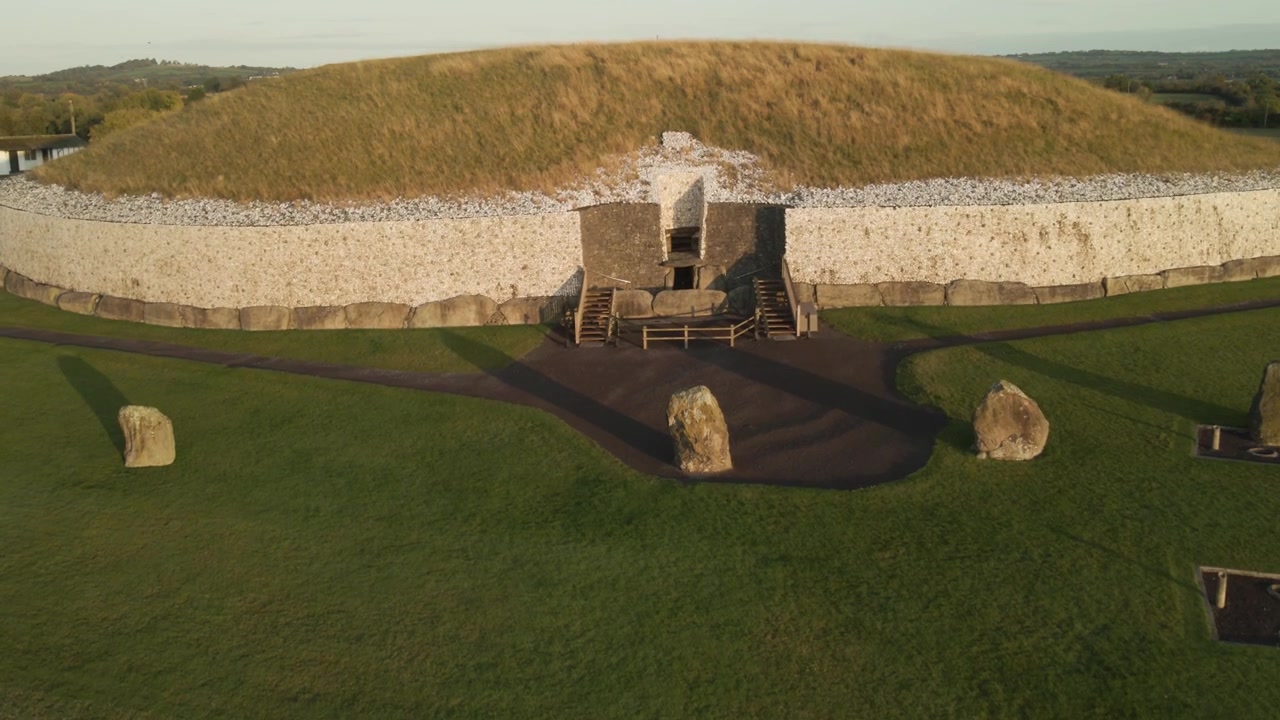 Antica tomba in pietra all'alba con tumulo d'erba e pareti di quarzo bianco in uno scenografico paesaggio irlandese
