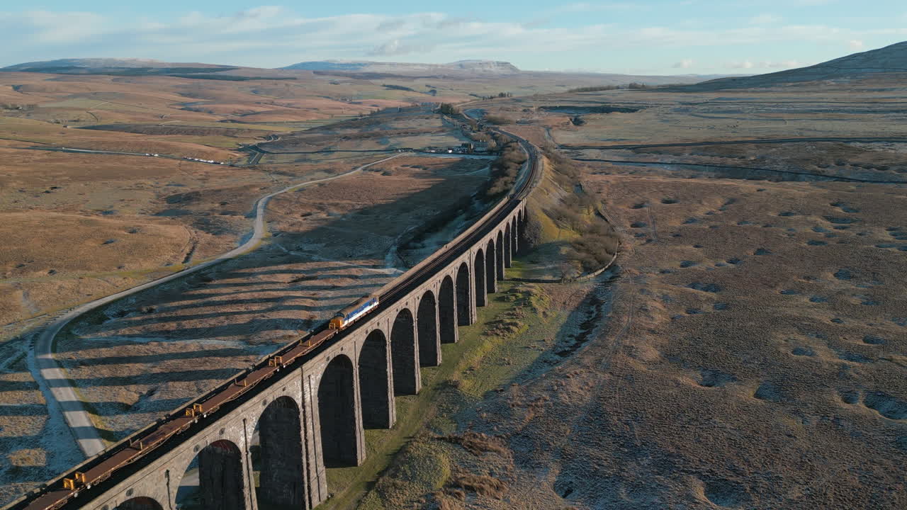 tren de carga que cruza el puente en la campiña inglesa en el viaducto ribblehead en invierno