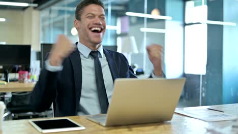 surprised african businessman having success on laptop