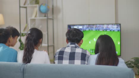 happy time of asian teenagers cheering and watching football game on tv and celebrating victory at home, sports and entertainment concept. back view. friends watching sports on tv