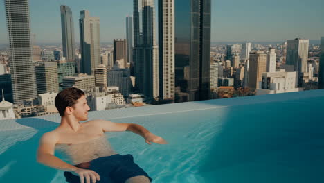 man in a rooftop infinity pool overlooking a city skyline