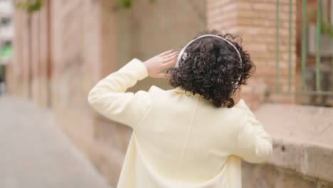 mujer joven sonriendo confiada escuchando música en la calle