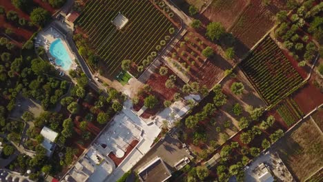 Drone-shot-of-italian-fields-in-the-countryside,-village-and-a-pool