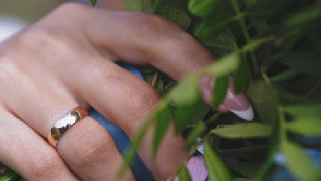 lady-with-wedding-ring-holds-flower-bouquet-at-ceremony