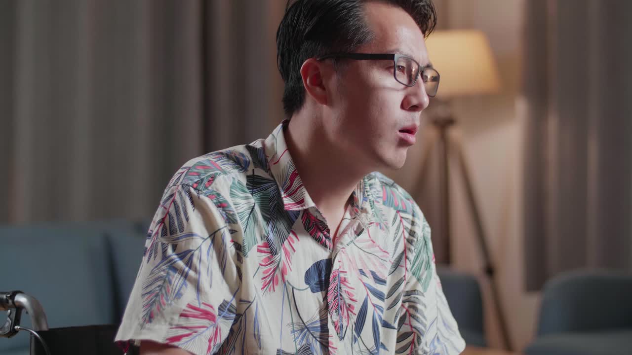 체어에 앉아 있는 아시아인 남자가 집에 있는 카메라 에 있는 데스크에서 비디오를 편집하는 동안 스트레칭을 하고 있다.