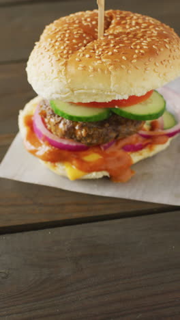 video vertical de una hamburguesa casera fresca con ensalada en un fondo de madera