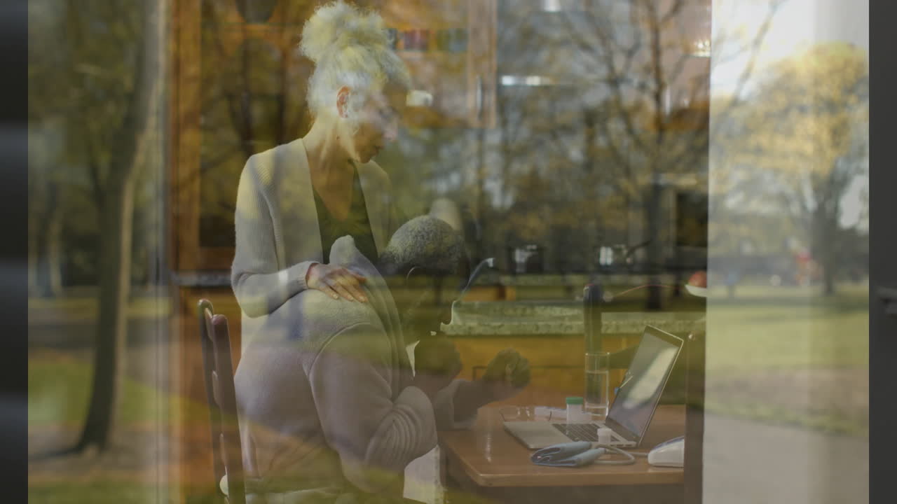 Nature scene reflecting through window, elderly couple at home watching animation