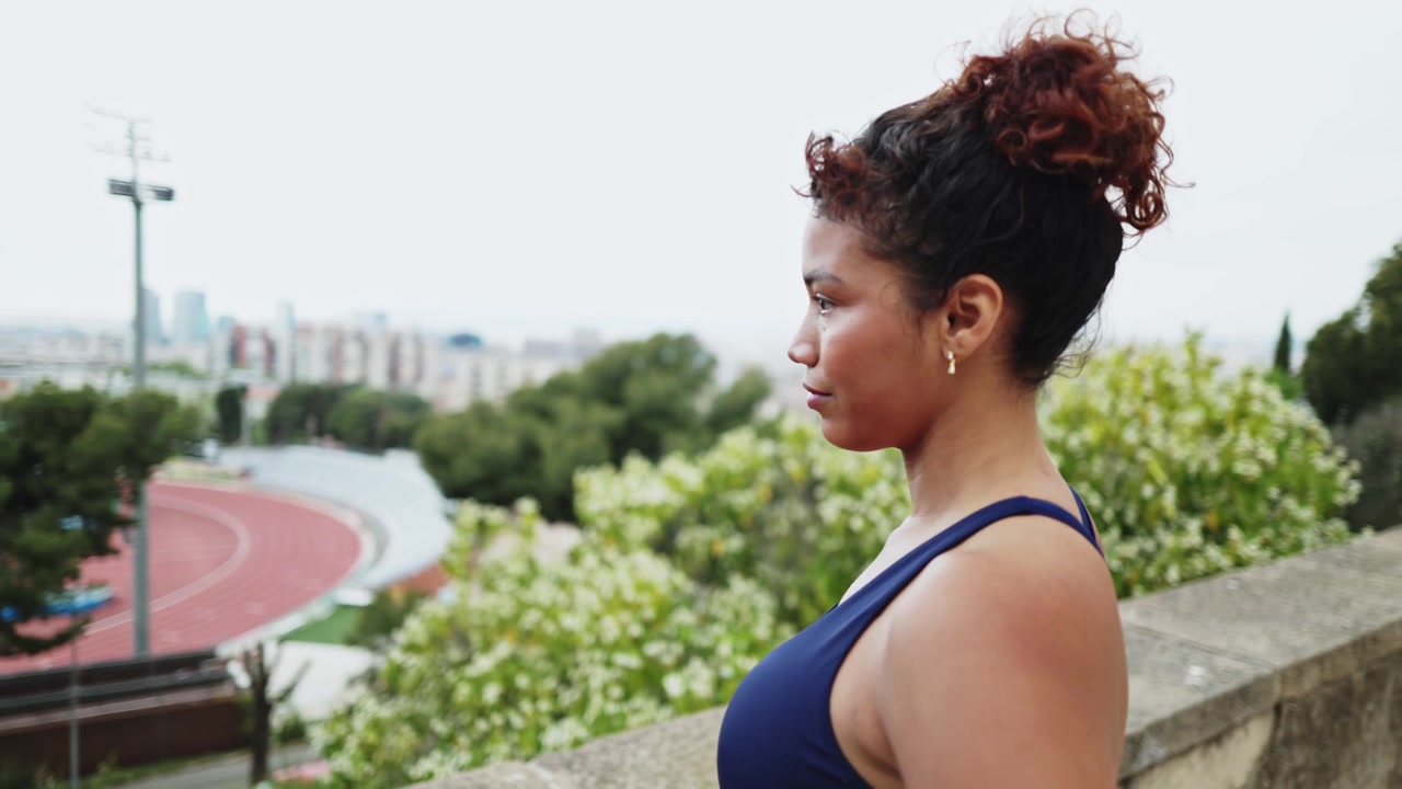 Jovem mulher tirando o casaco em um parque com vista para a cidade