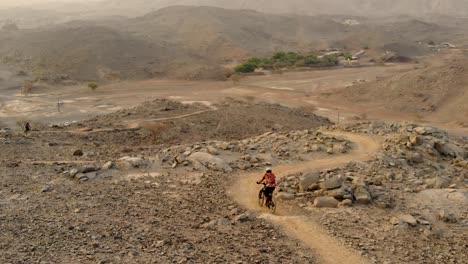 Ciclista-De-Montaña-Macho-Adulto-Montando-Cuesta-Abajo-Enduro-Todoterreno-Con-Protección-De-Casco-Completo-Durante-El-Atardecer-En-Showka,-Shawka,-Ras-Al-Khaimah,-Eau