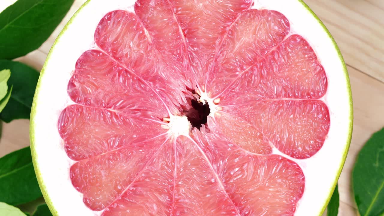 정원에서 나무 테이블에 잎을 가진 빨간 포멜로 과일을 회전, 나무 배경 4k 해상도에서 잎과 함께 빨간 포মেল로 과일.