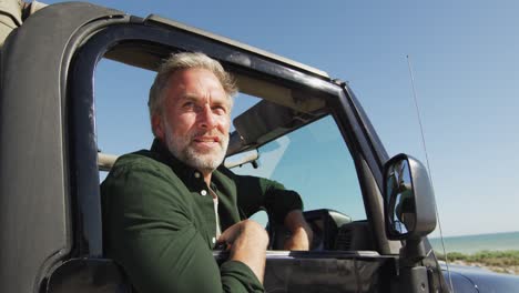 happy caucasian man in car admiring the view on sunny day at the beach