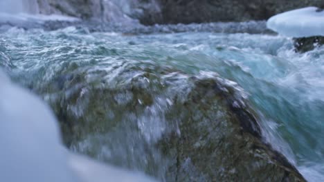 Nahaufnahme-Und-Zeitlupe-Von-Flusswassertropfen-über-Einem-Niedrigen-Felsen-In-Einem-Schnell-Fließenden-Fluss-Mit-Sauberem-Süßwasser