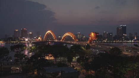Colorful-night-time-lapse-of-iconic-Dragon-Bridge-Cau-Rong-changing-colors-and-skyline-during-sunset-in-Danang,-Vietnam