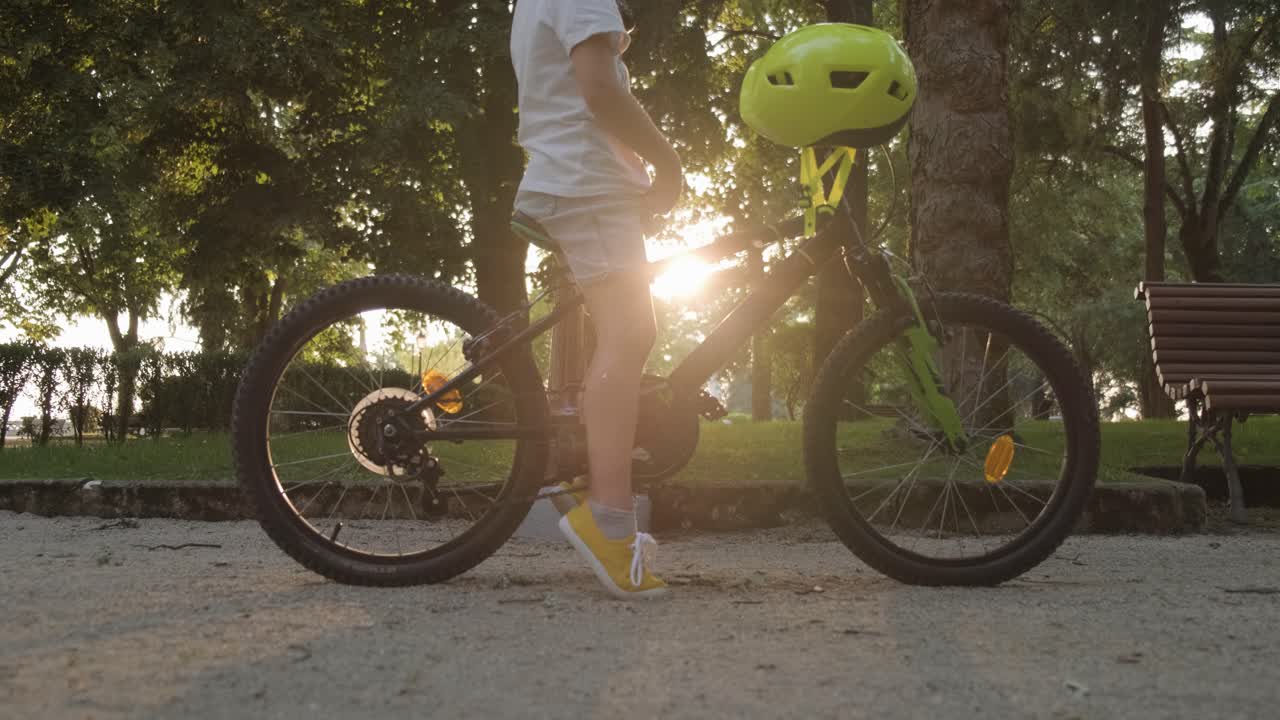 Boy child sitting on a bicycle, putting on his helmet, Hero pedestal shot