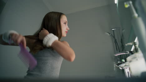 teenage girl brushing her hair in the bathroom