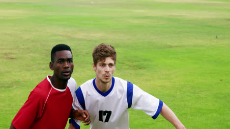 two football players jumping to strike a ball