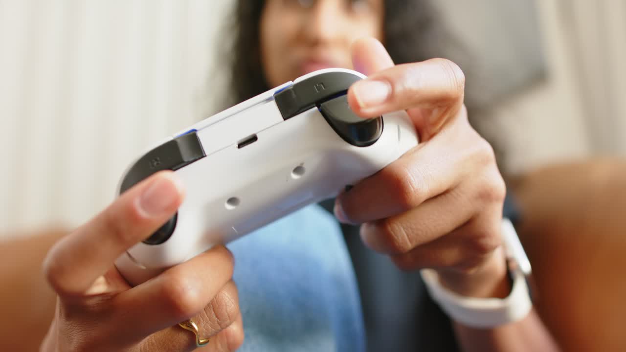Person on couch is reaching and bringing gamepad in frame to play, pressing bumpers, turning thumbs