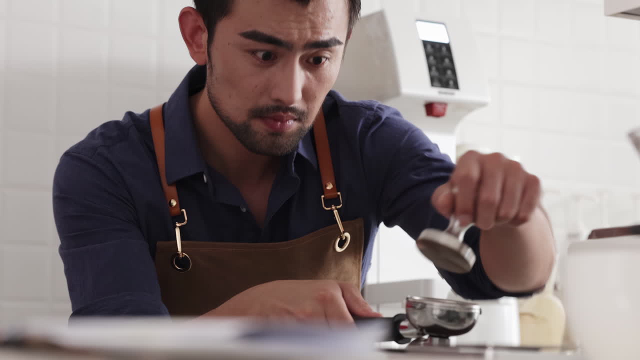 Professional barista prepare espresso brewing coffee use hand-held tamper, tamping freshly ground coffee beans powder in portafilter in cafe restaurant business shop, focusing on precision of process