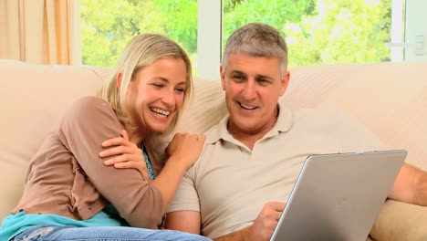 Attractive-couple-looking-and-laughing-at-laptop