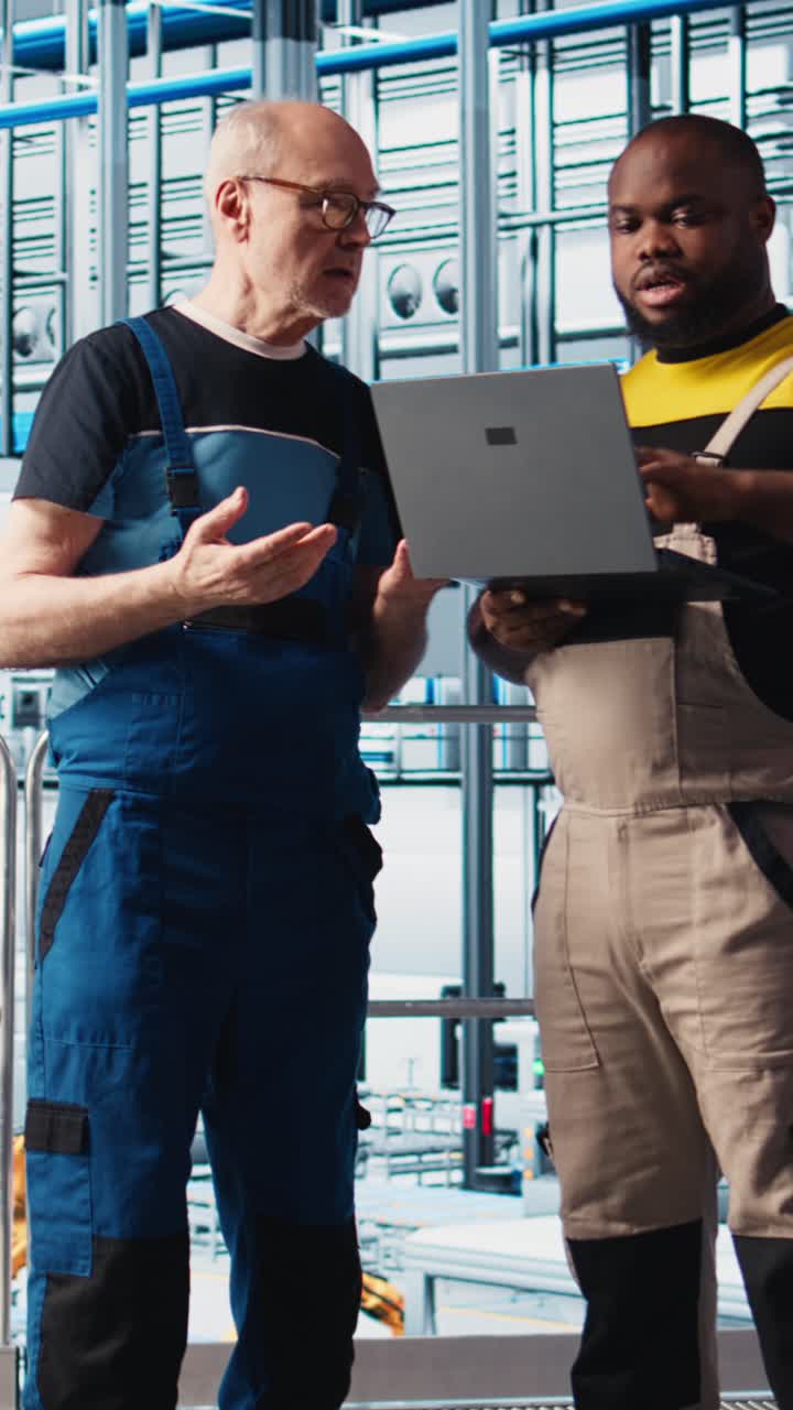 Vertical video Smart factory senior engineer teaches intern to implement automated workflows