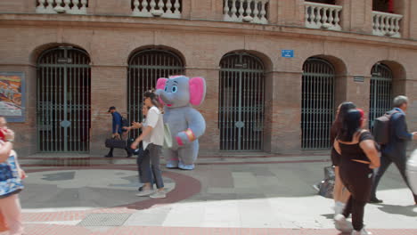 people walking by a street performer in an elephant costume