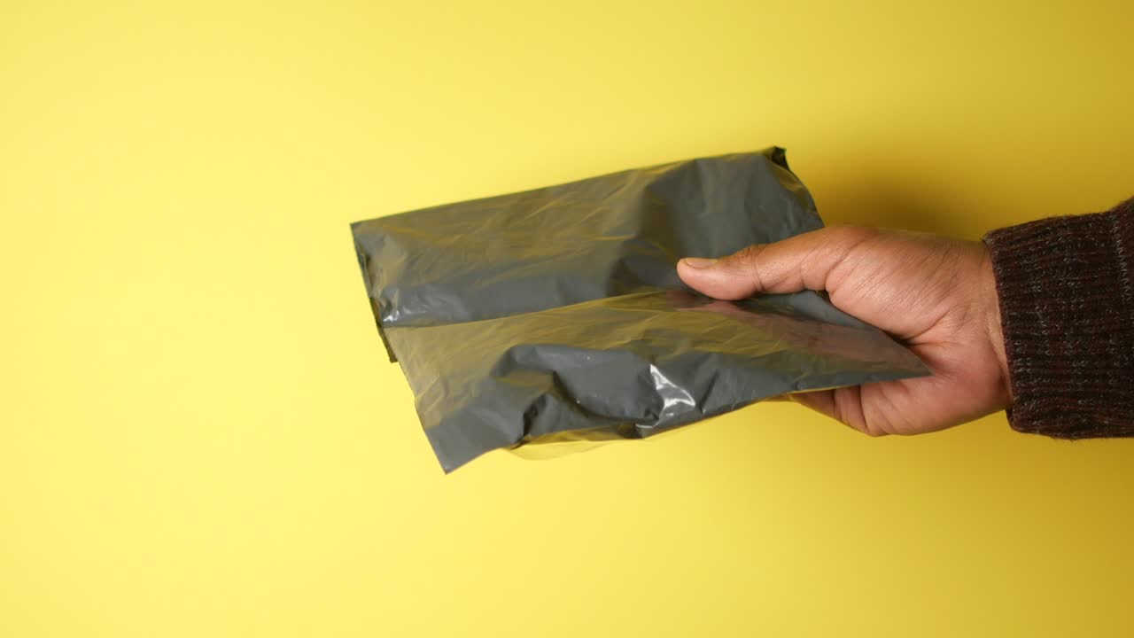 mano con una bolsa de correo de plástico gris