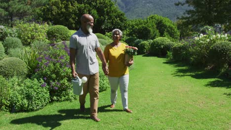 African-american-senior-couple-smiling-while-holding-hands-and-walking-together-in-the-garden