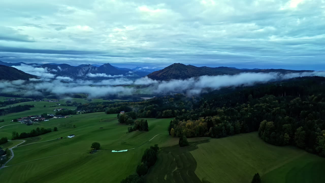 시골 마을 근처의 나무와 산 위에 떠다니는 낮은 안개 구름
