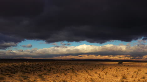 dramatic dark rain clouds gather for a storm above the mojave desert - aerial view