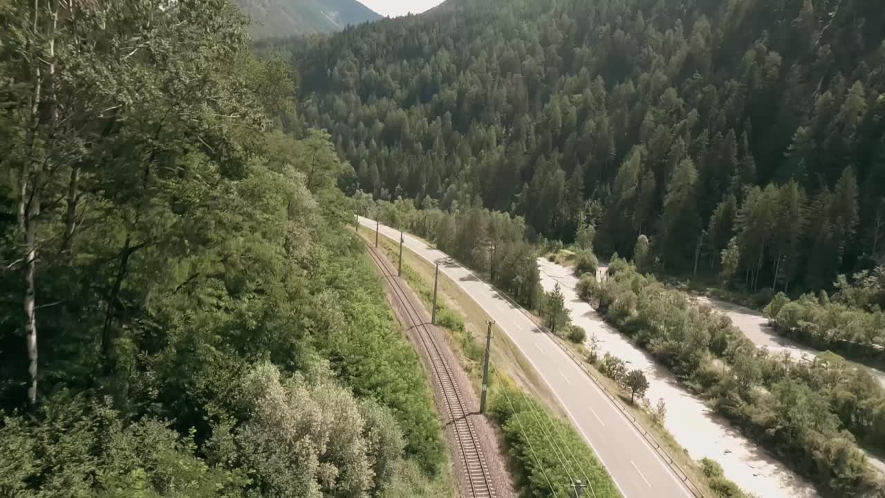 imágenes de cámara de acción de un dron de carreras fpv volando rápido en un valle cerca de una carretera y sobre un ferrocarril en austria en verano
