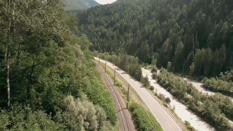 Action-camera-footage-from-FPV-racing-drone-flying-fast-in-a-valley-close-to-a-road-and-above-a-railroad-in-Austria-in-summer