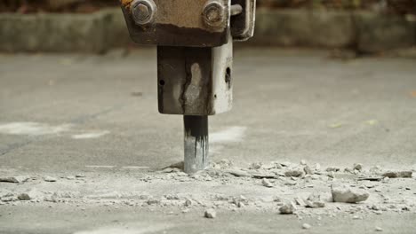 Close-up of excavator hydraulic arm rock breaker working on concrete road