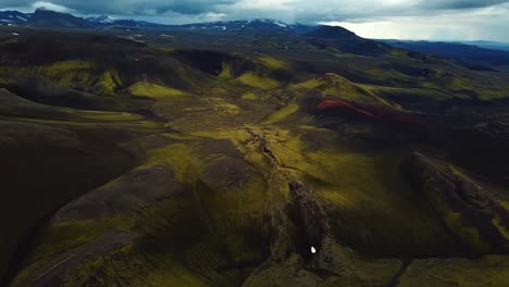 Aerial-landscape-view-over-Icelandic-highlands,-with-dark-hills-and-mountains,-on-a-cloudy-day