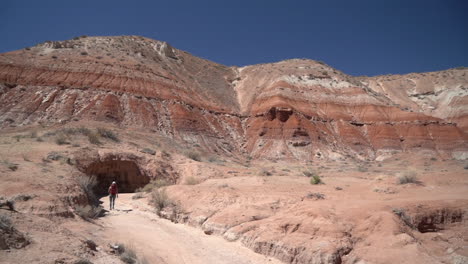 Lonely-Female-Hiker-on-Hiking-Trail-Under-Sandstone-Hills-in-Landscape-of-Arizona-USA,-Back-View