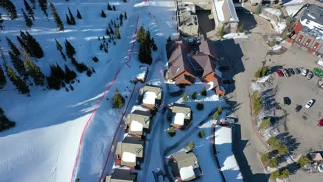 bird’s eye drone view of a snowy mountain chair lift carrying skiers above powdery slopes and pine-lined trails, surrounded by scenic winter peaks in a peaceful alpine landscape