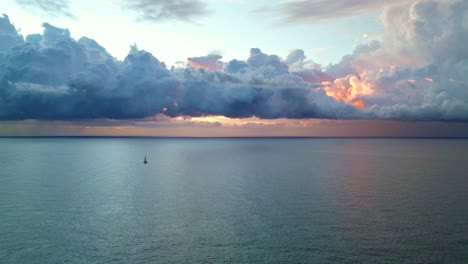 un barco solitario navegó por el mar con una nube roja sobre él