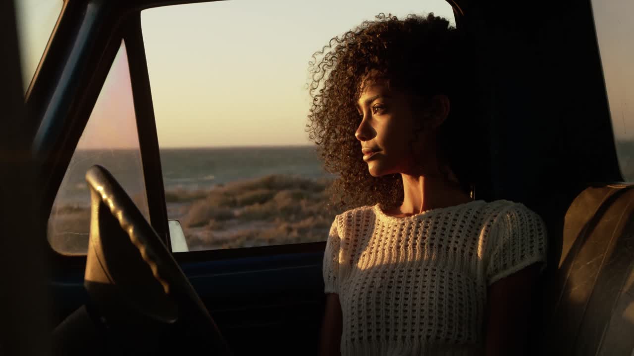 Woman sitting in pickup truck at beach 4k
