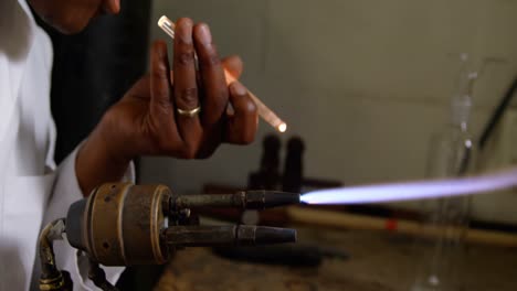 Side-view-of-black-male-worker-blowing-glass-in-glass-factory-4k