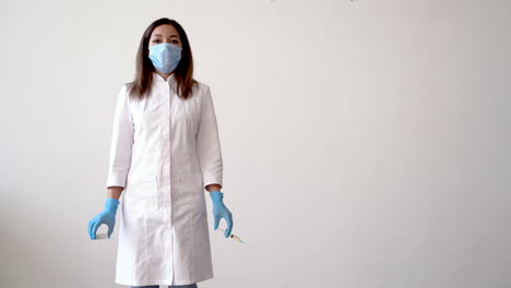 female nurse holding a syringe and a vaccine vial for covid 19