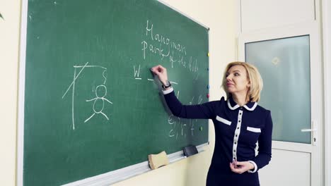 teacher is writing letter on blackboard with chalk. education in elementary school concept