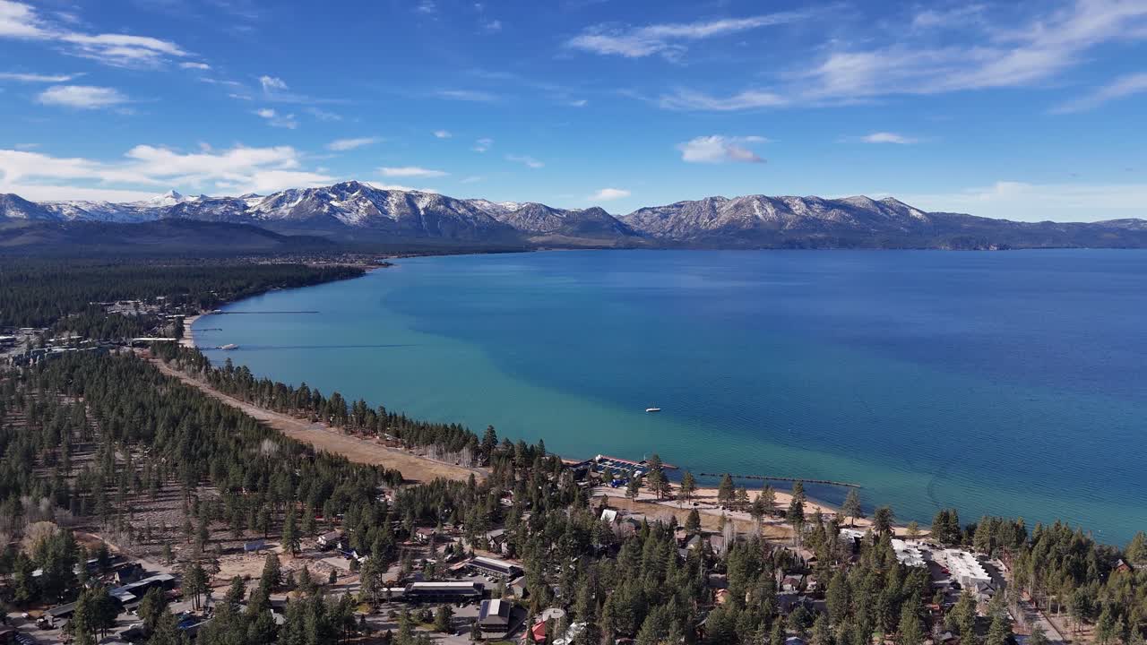 Aerial panoramic view of South Lake Tahoe coastline and town with snowy mountains