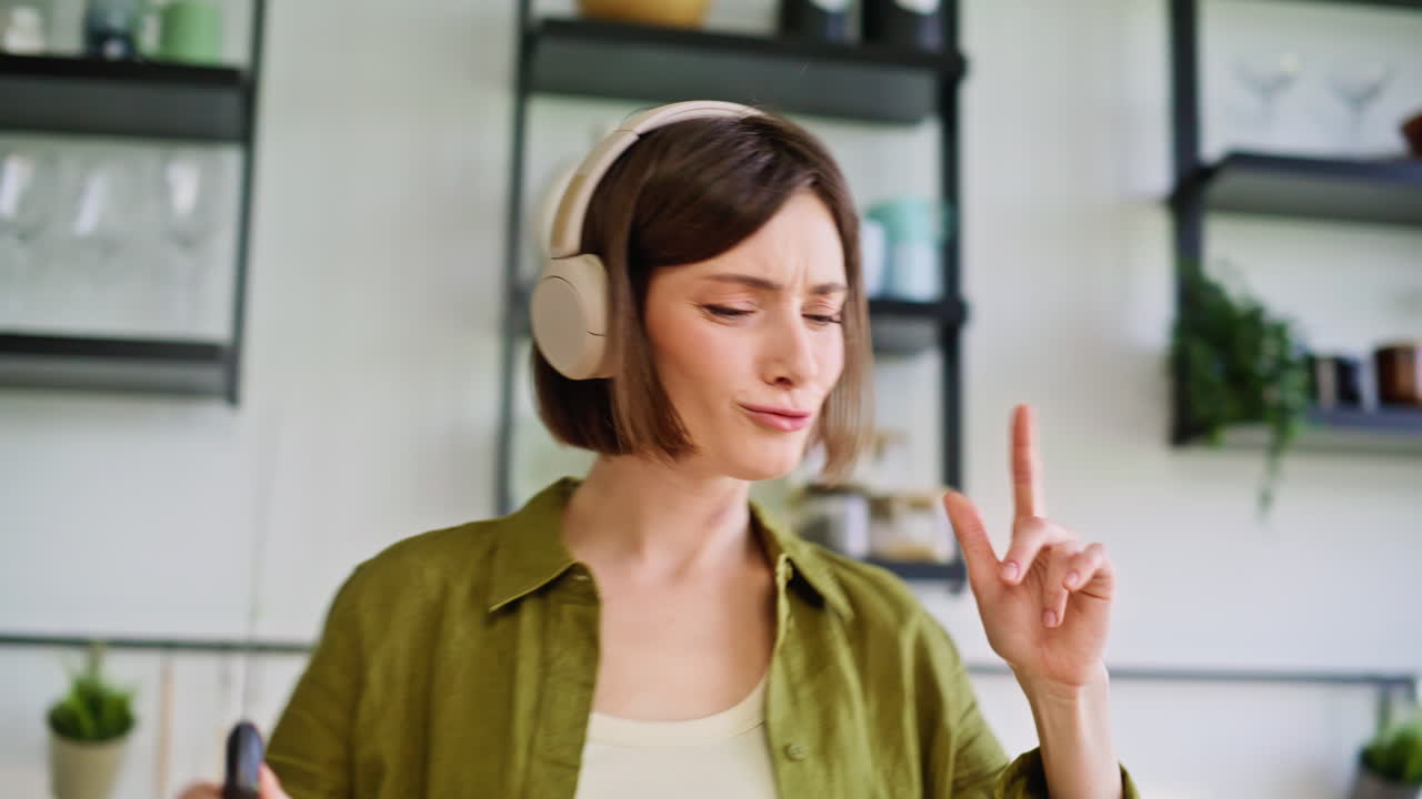 Damehænder hakker grønt på overfladen om morgenen, nærbillede. Kok lytter til musik