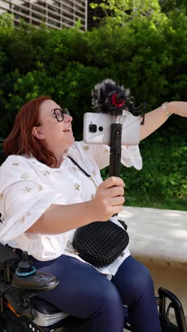 woman in wheelchair vlogging with smartphone and microphone