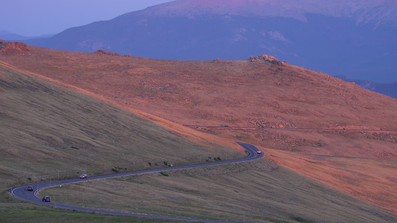 coches conduciendo en el parque nacional de las montañas rocosas al atardecer