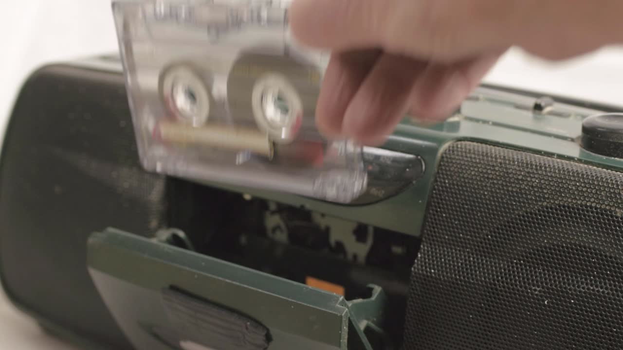 Hand putting retro cassette tapes into radio cassette player medium shot