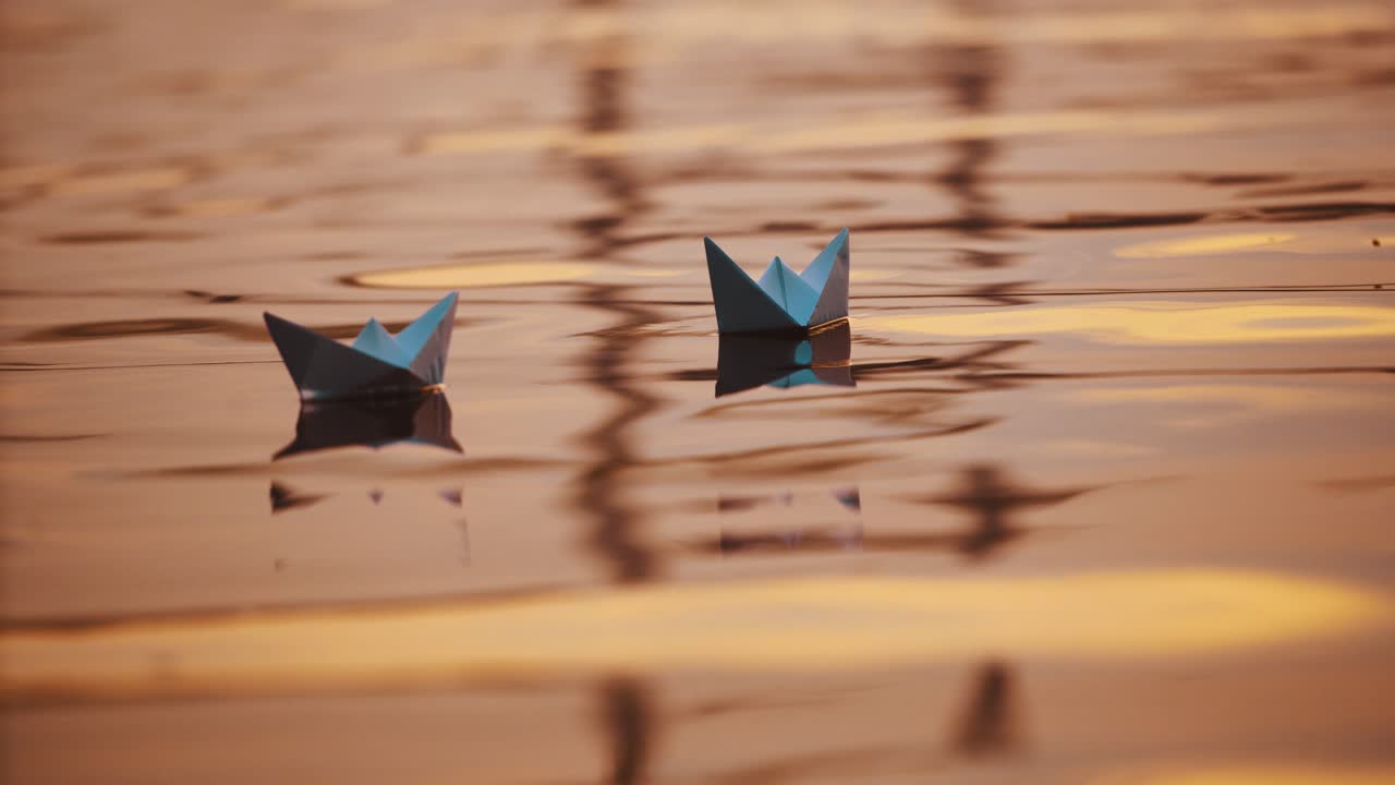 Two blue paper ships on water outdoors. Origami boats floating on the water surface in the evening. Close-up.