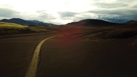 Vista-Aérea-Del-Paisaje-Sobre-Los-Vehículos-Con-Tracción-En-Las-Cuatro-Ruedas-En-Un-Camino-De-Tierra-En-Las-Tierras-Altas-De-Islandia