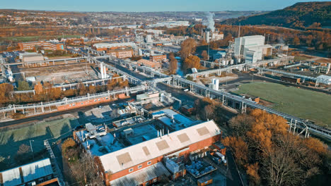 aerial footage moving towards a large industrial chemical plant, showing pipelines, metal structures, cooling towers and chemical storage